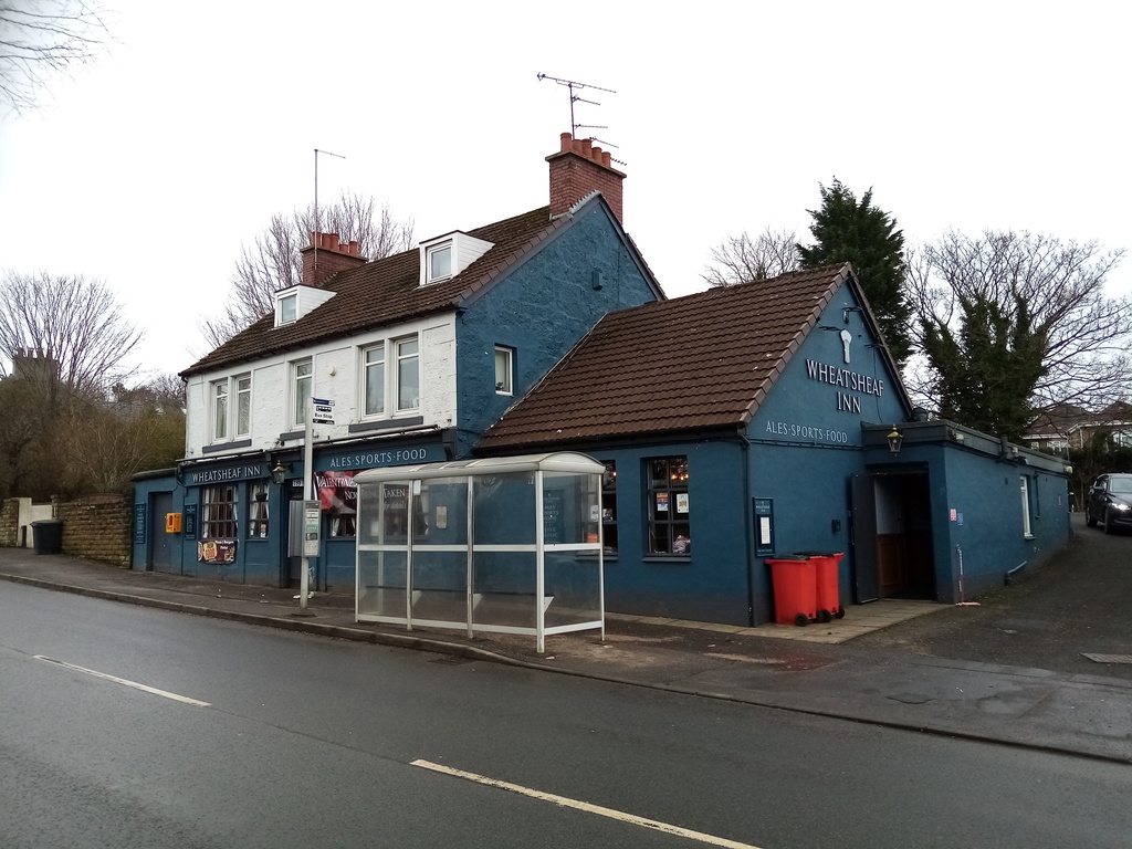 dark teal coloured pub partly obscured by bus stop